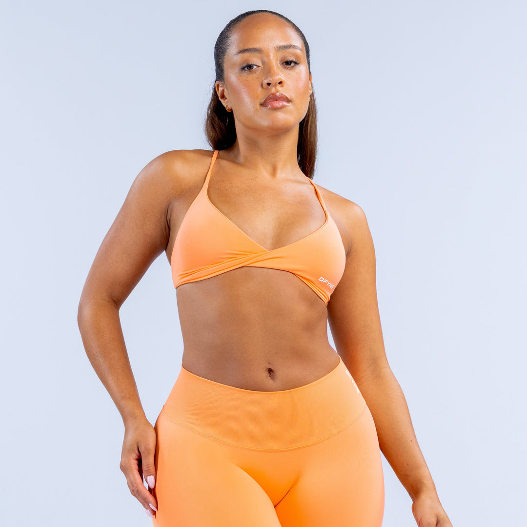 Orange twist-front sports bra with V-neck and thin adjustable straps